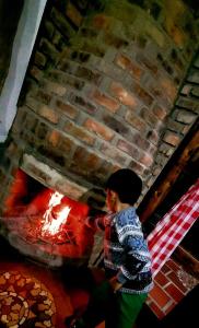 Ventaquemada的住宿－Cabaña Mirador, las Acacias de Teli，坐在砖壁炉前的男孩