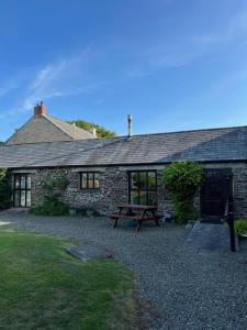 une maison en pierre avec une table de pique-nique devant elle dans l'établissement Shire Cottage - Crackington Haven, Cornwall, à Saint Gennys