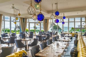 ein Restaurant mit Tischen, Stühlen und Kronleuchtern in der Unterkunft Harbour Hotel & Spa Sidmouth in Sidmouth