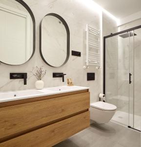 een badkamer met een wastafel, een toilet en 2 spiegels bij The Rentals Collection - Opera in San Sebastian