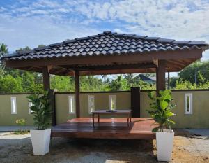 une pergola en bois avec une table en bois et deux plantes dans l'établissement Nipah Homestay Kuala Besut, à Kampung Kuala Besut