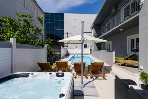 a hot tub with chairs and an umbrella next to a building at Villa Mihaela with private pool, jacuzzi and free secure parking in Trogir