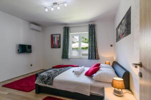 a bedroom with a bed with red pillows and a window at Villa Mihaela with private pool, jacuzzi and free secure parking in Trogir +37 photos