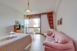 een slaapkamer met een bed en een roze bank bij Villa Olivella in Sale Marasino