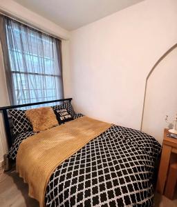Schlafzimmer mit einem schwarzen und weißen Bett und einem Fenster in der Unterkunft Spacious Studio Flat in London in London