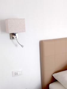 uma luz ligada a uma parede ao lado de uma cama em Vinci Residence em Fiumicino