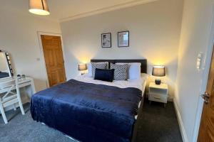溫伯恩大教堂的住宿－Large apt, sleeps 4, in picturesque Wimborne town - The Westborough Nook，一间卧室配有一张带蓝色毯子和两盏灯的床。