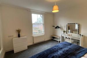 a bedroom with a bed and a desk and a mirror at Large apt, sleeps 4, in picturesque Wimborne town - The Westborough Nook in Wimborne Minster