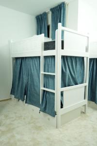 a white bunk bed in a room with blue curtains at Curve Hostel JBR in Dubai