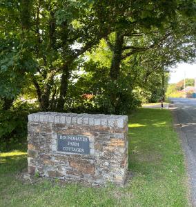 un panneau en pierre dans l'herbe à côté d'une rue dans l'établissement Shire Cottage - Crackington Haven, Cornwall, à Saint Gennys