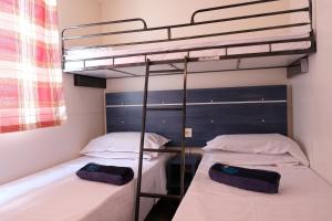 two beds in a room with a bunk bed at Happy Camp mobile homes in Camping Village Baia Paradiso in Badesi