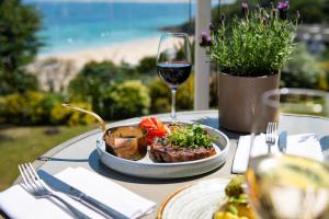 a table with a plate of food and a glass of wine at Harbour Hotel & Spa St Ives in St Ives