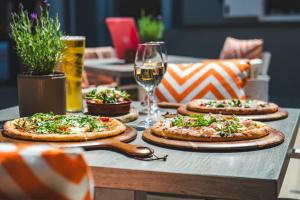 three pizzas on a table with glasses of wine at Harbour Hotel & Spa St Ives in St Ives
