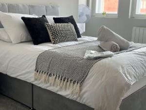 a white bed with black and white pillows on it at Spacious, bright 2 bed flat with 1 S/king bed. in Brentwood