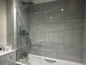 a bathroom with a shower with a tub and a sink at Spacious, bright 2 bed flat with 1 S/king bed. in Brentwood