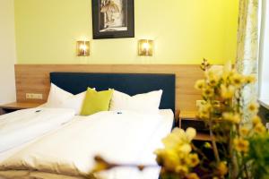 a bedroom with a bed with white sheets and yellow walls at Hotel Grader in Neustadt an der Waldnaab