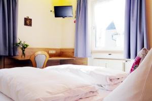 a bedroom with two beds with blue curtains and a tv at Hotel Grader in Neustadt an der Waldnaab