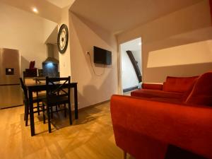 a living room with a red couch and a dining room table at Appartements Baron Bouvier in Vesoul