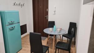kuchnia ze stołem i krzesłami oraz niebieską lodówką w obiekcie Apartamenty Centrum Plac Wolności ApartHotel w Kielcach