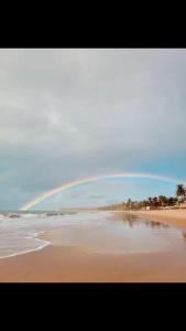 einen Regenbogen am Himmel über einem Strand in der Unterkunft Casa Prema - Experiência vegana e terapêutica à beira-mar in Maceió