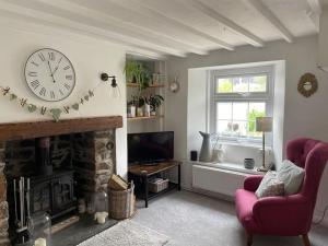 a living room with a clock and a fireplace at Tiny romantic cottage for two. in Lostwithiel
