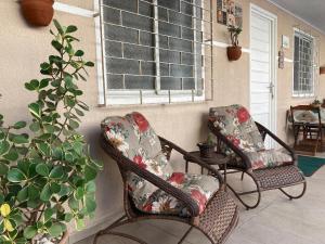 2 sillas de mimbre sentadas en un porche con ventana en Casa Cores Guaratuba Piscina Aquecida WiFi Rápido TV Smart, en Guaratuba