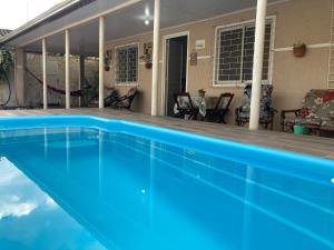 una piscina azul frente a una casa en Casa Cores Guaratuba Piscina Aquecida WiFi Rápido TV Smart, en Guaratuba