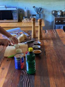a person preparing food on a wooden table in a kitchen at Magical Cabin in the Woods in Kleinbaai