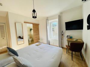 a bedroom with a large white bed and a desk at Hôtel La Bastide de Vaison in Vaison-la-Romaine