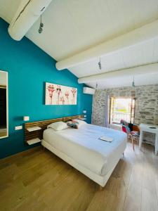 ヴェゾン・ラ・ロメーヌにあるHôtel La Bastide de Vaisonの青い壁のベッドルーム1室(大型ベッド1台付)