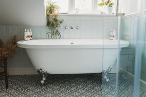 eine weiße Badewanne in einem Badezimmer mit Fenster in der Unterkunft Two Luxury Cosy Cottages in Tewkesbury + 32 Fotos