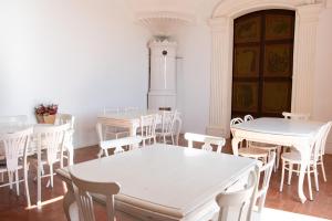 a room with white tables and chairs and a clock tower at Can Traver de Besalú in Maia de Montcal