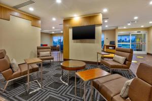 a lobby with a waiting room with chairs and a flat screen tv at TownePlace Suites by Marriott Grand Rapids Airport Southeast in Grand Rapids