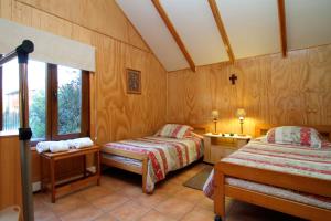 two beds in a room with wooden walls and windows at Apart Hotel Villa Los Ciruelos in Valdivia
