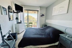 um quarto com uma cama preta e uma varanda em Cosy family nest with balcony and shared pool em Mandelieu-la-Napoule