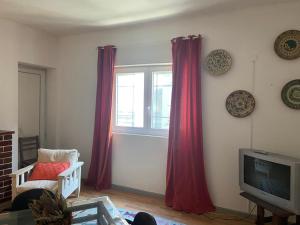 ein Wohnzimmer mit roten Vorhängen und einem TV in der Unterkunft Eskama guest house in Esposende