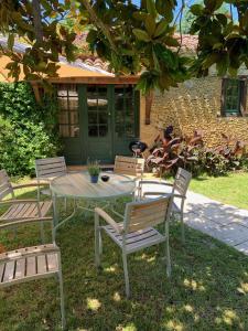 una mesa y sillas en un patio con una casa en La Gersoise, en Estang