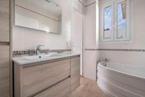 a white bathroom with a tub and a sink and a bath tubermott at Parenthèse en famille et détente au Pouliguen in Le Pouliguen +23 photos