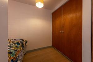 a bedroom with a bed and a wooden cabinet at Lovely self-contained basement studio with kitchen in London