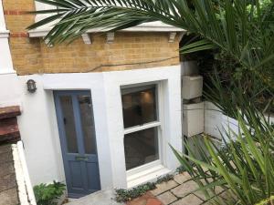 a blue door on the side of a house at Lovely self-contained basement studio with kitchen in London