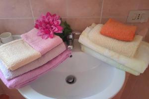 einen Haufen Handtücher auf einem weißen Waschbecken in der Unterkunft Casetta vista mare 2 Climatizzata in Castellammare del Golfo