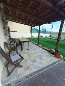 eine Terrasse mit einem Tisch und Stühlen unter einem Dach in der Unterkunft Sossego e tranquilidade - Valley Guest House - Perto de Lisboa in Arruda dos Vinhos