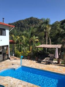 a swimming pool in front of a house with palm trees at Lua Branca_Recanto in Juiz de Fora