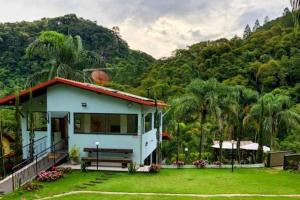 ein kleines weißes Haus mit einer Bank im Hof in der Unterkunft Lua Branca_Recanto in Juiz de Fora
