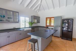 a large kitchen with a black counter and a refrigerator at Villa Marie - Habitation Saint Charles in Petit-Bourg