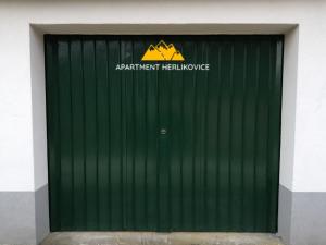 a green garage door with a sign on it at Apartment Herlikovice in Trutnov