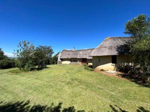 an old barn with a thatched roof and a yard at Mpofu Lodge in Bergview