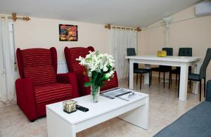 a living room with red chairs and a table with flowers at Apartamento La Relojera 1 in Jarandilla de la Vera