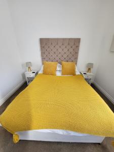 een slaapkamer met een groot geel bed en 2 tafels bij the devon and cornwall inn in Millbrook