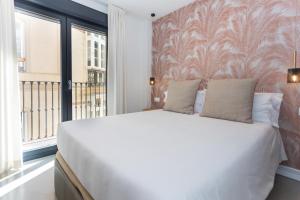 um quarto com uma grande cama branca e uma janela em Apartamentos 7 dreams em Málaga